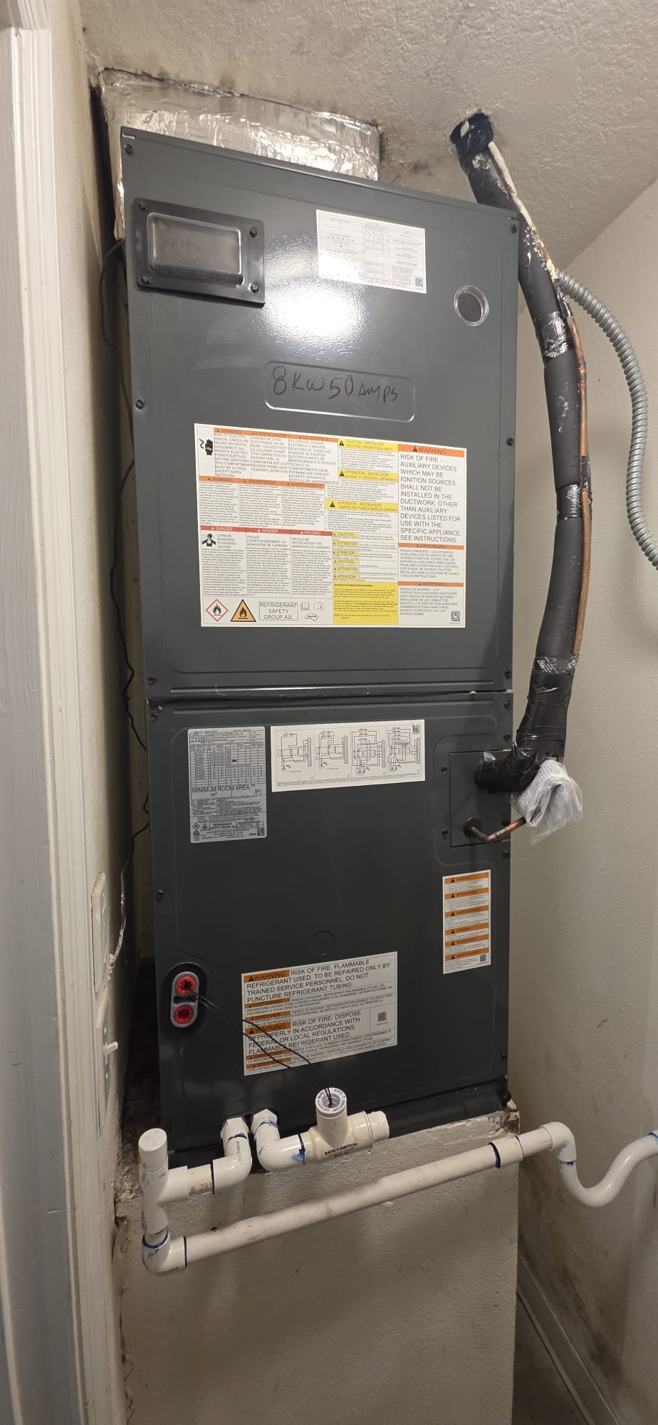 Indoor air handler installation with copper refrigerant lines and PVC condensate drain