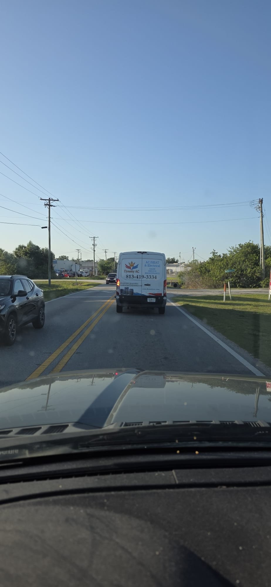 Dynasty AC branded service van on the road, rear signage visible