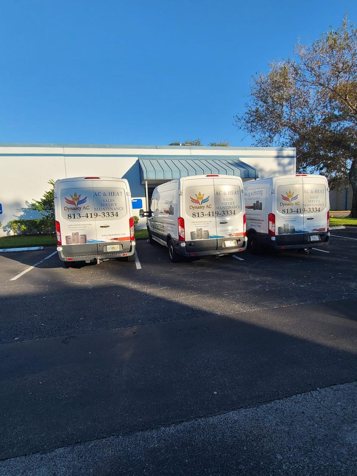 Three branded Dynasty AC service vans parked at the shop