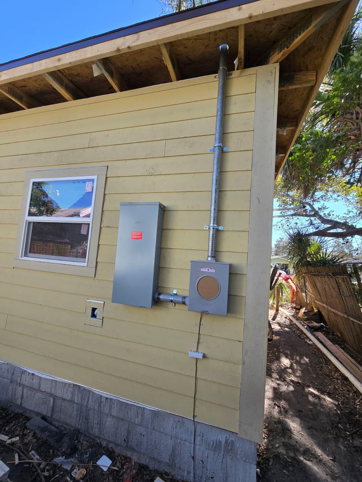 Exterior electrical meter and panel installation with conduit running to the roof