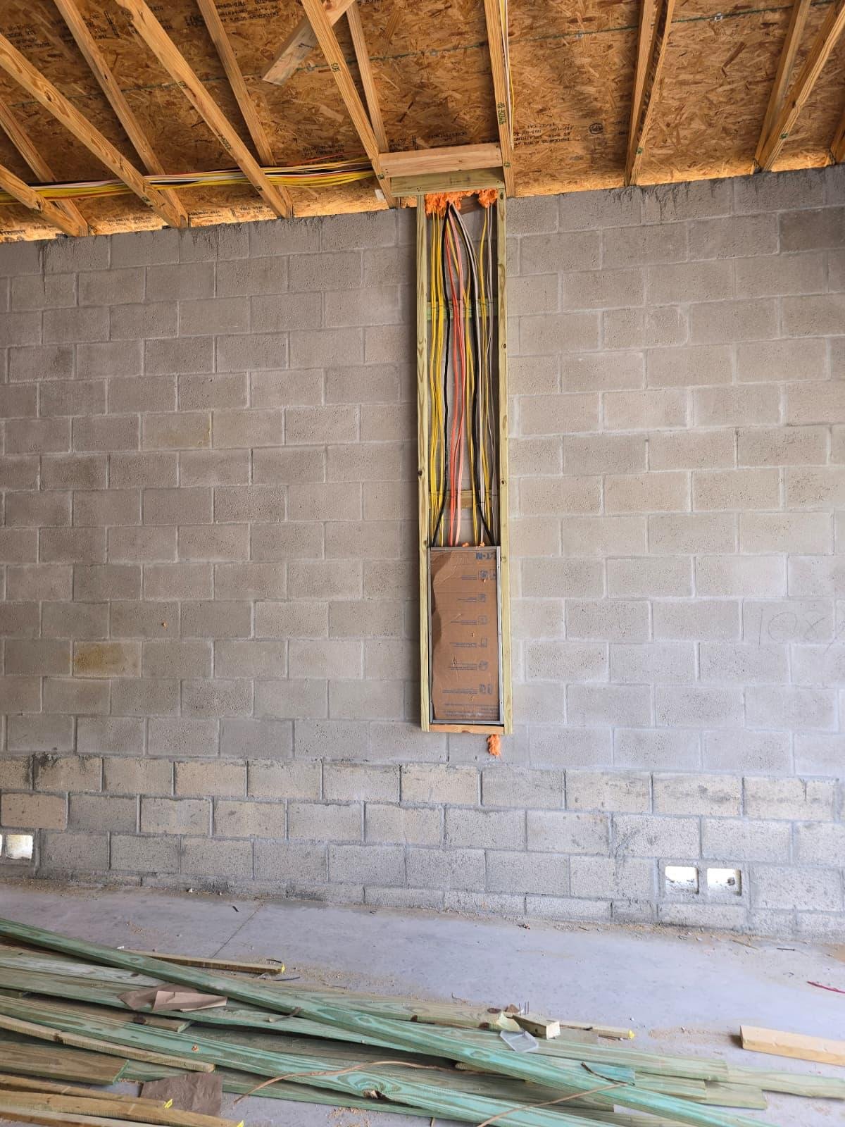 Electrical wiring routed through wall framing to a panel enclosure, unfinished building