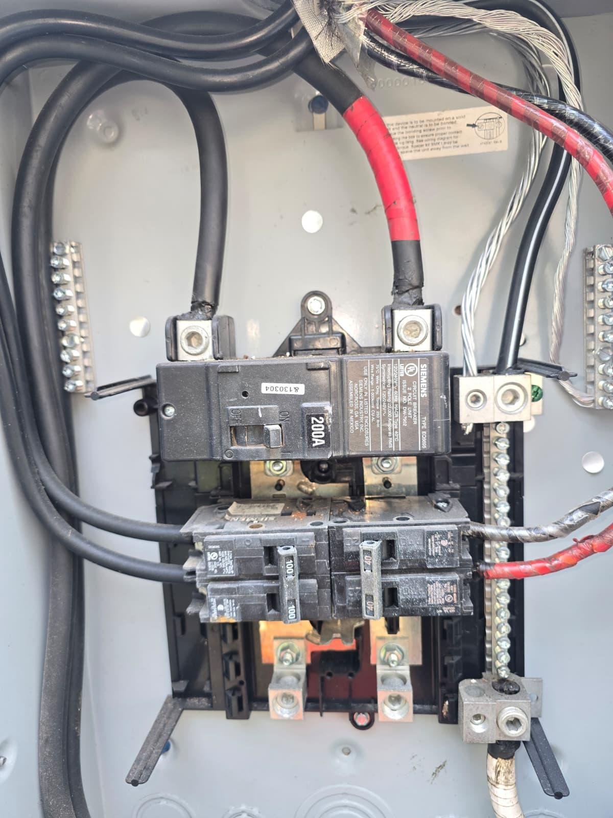 Open electrical panel interior showing 200A main breaker and branch wiring