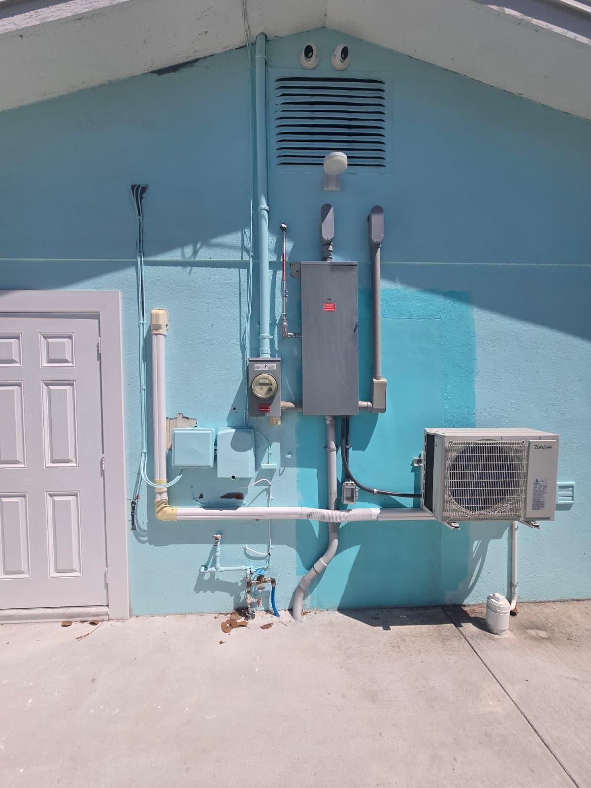 Electrical panel and disconnect switches beside an outdoor mini-split condenser unit