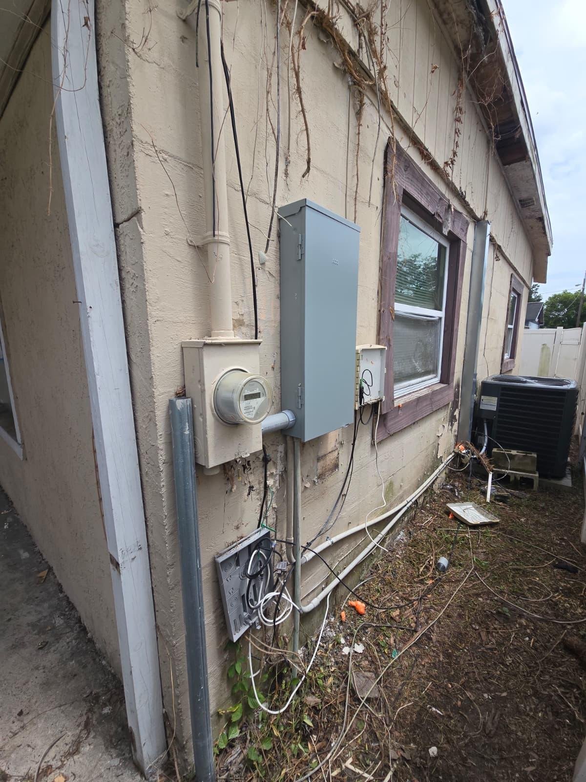 Electrical meter and panel installed on exterior wall with conduit and junction box