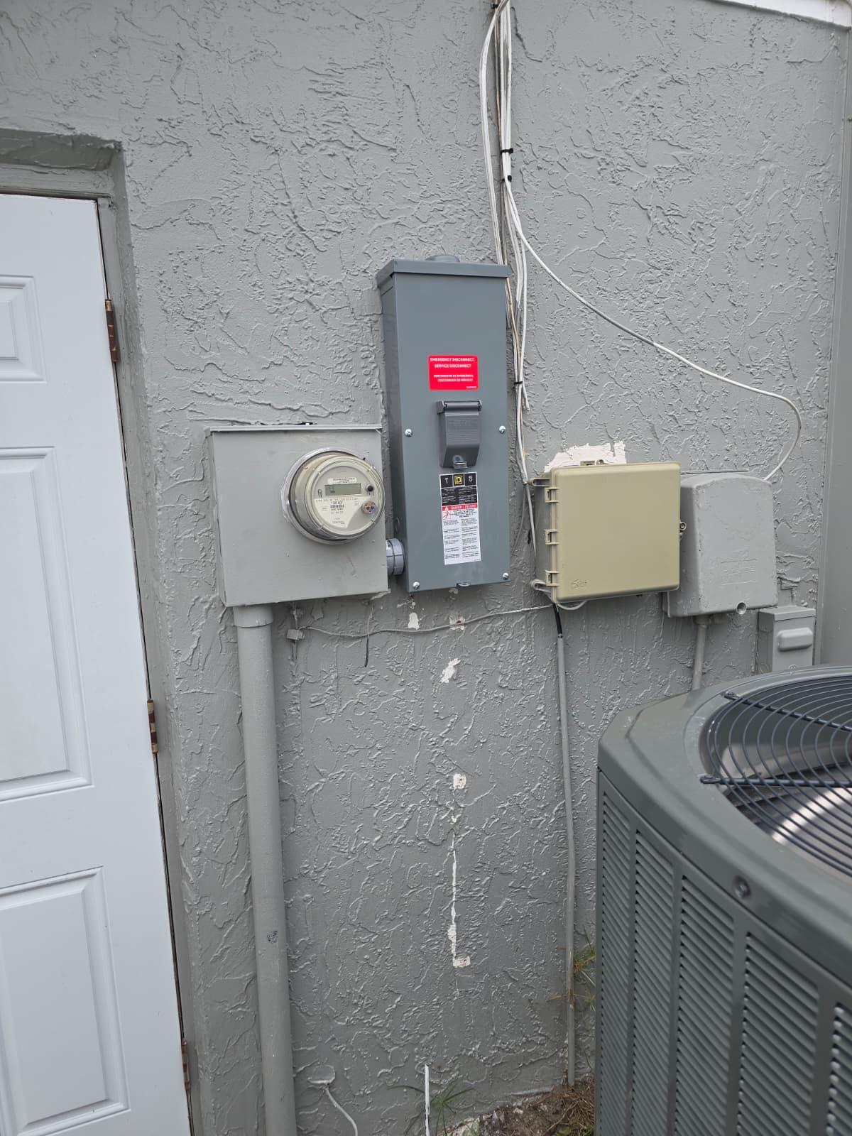 Electrical meter, disconnect, and AC condenser installed together on an exterior wall